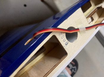 Temporarily affix the servo wire to the outside of the wing so the wire doesn't fall back in the plane.